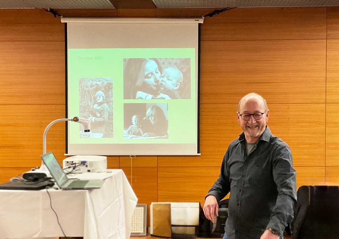Erich Meister at his farewell apéro with family portraits in the background.